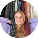 Opruimcoach / professional organizer Saskia van Amerongen staat lachend voor een open kledingkast.