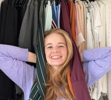 Opruimcoach Saskia van Amerongen Opruimcoach / professional organizer Saskia van Amerongen staat lachend voor een open kledingkast.