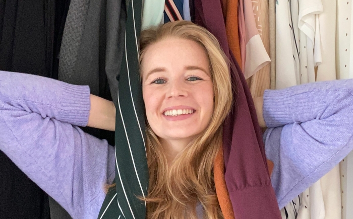 Opruimcoach Saskia van Amerongen Opruimcoach / professional organizer Saskia van Amerongen staat lachend voor een open kledingkast.