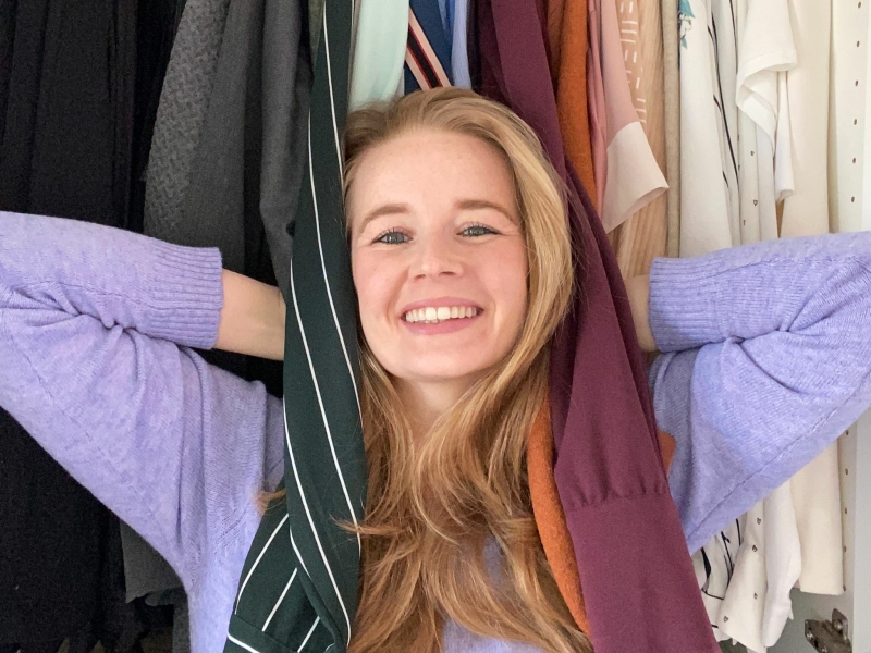 Opruimcoach Saskia van Amerongen Opruimcoach / professional organizer Saskia van Amerongen staat lachend voor een open kledingkast.
