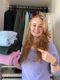 Opruimcoach / professional organizer Saskia van Amerongen staat lachend voor een open kledingkast.