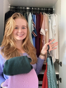 Opruimcoach / professional organizer Saskia van Amerongen voor een kledingkast met opgevouwen kleding in haar handen.