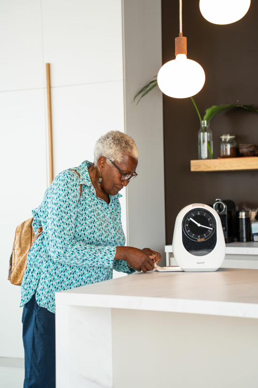 Oudere man gebruikt Medido medicijndispenser in moderne keuken