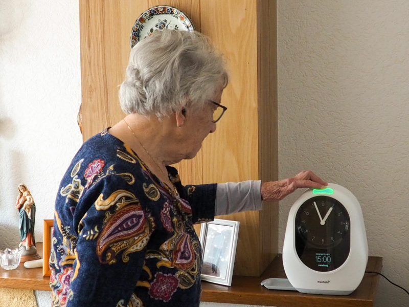 Senioren vrouw bedient Medido medicijndispenser in huiselijke omgeving