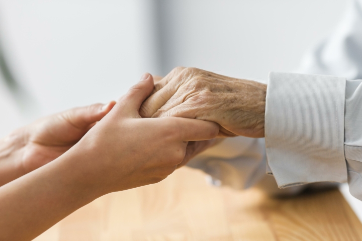 verpleegster die de handen van de hogere man voor comfort houdt