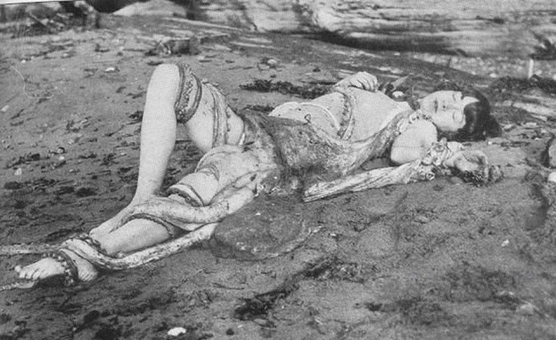 black an white photo of a girl lying on the beach with an octopus on top of her