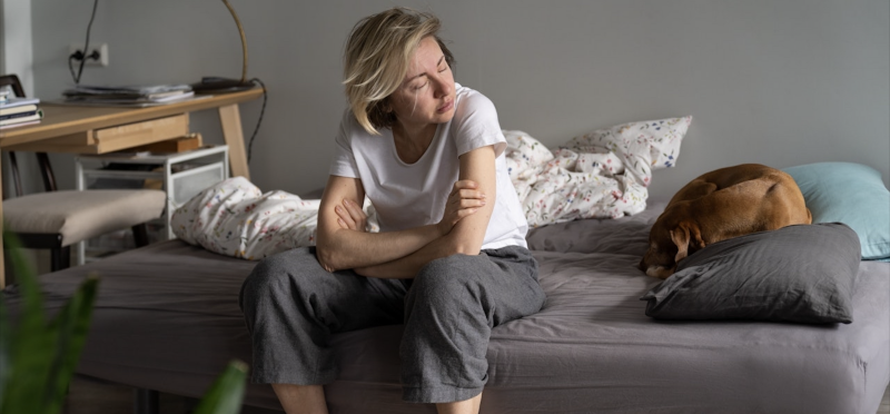 Vrouw zit stil op de rand van het bed en voelt zich niet uitgerust ondanks voldoende slaapuren