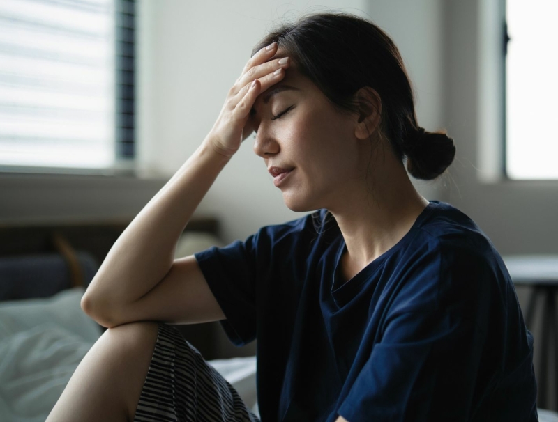 Niet uitgerust wakker worden ondanks slaap Volwassene zit ’s ochtends op de rand van het bed en voelt zich niet hersteld na slapen