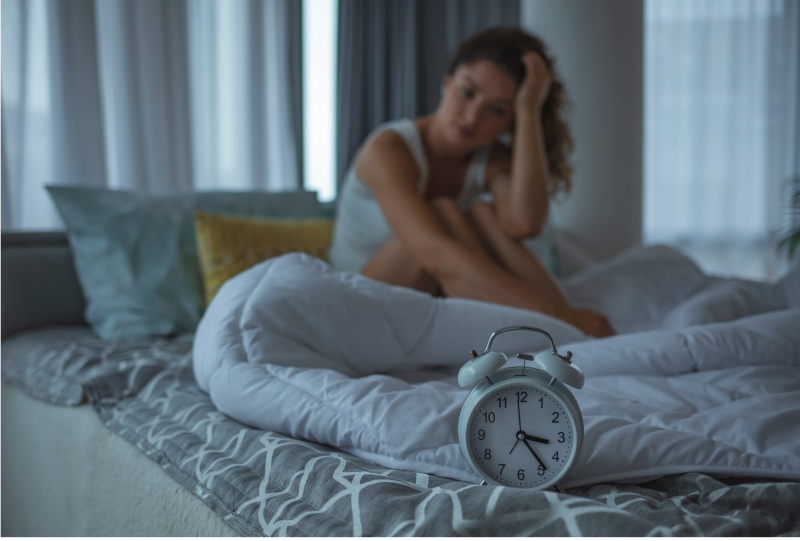 Mevrouw wakker op bed die niet kan slapen met een wekker