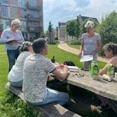 mensen zitten aan picknicktafel en luisteren naar ilse