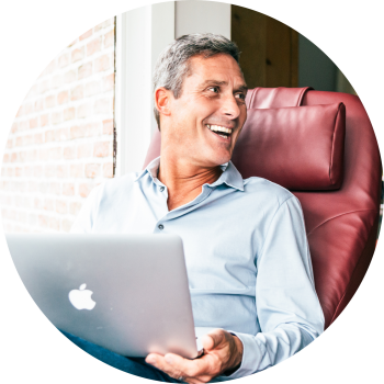 Senioren man thuis met grijs haar in een rode sta op stoel met een laptop