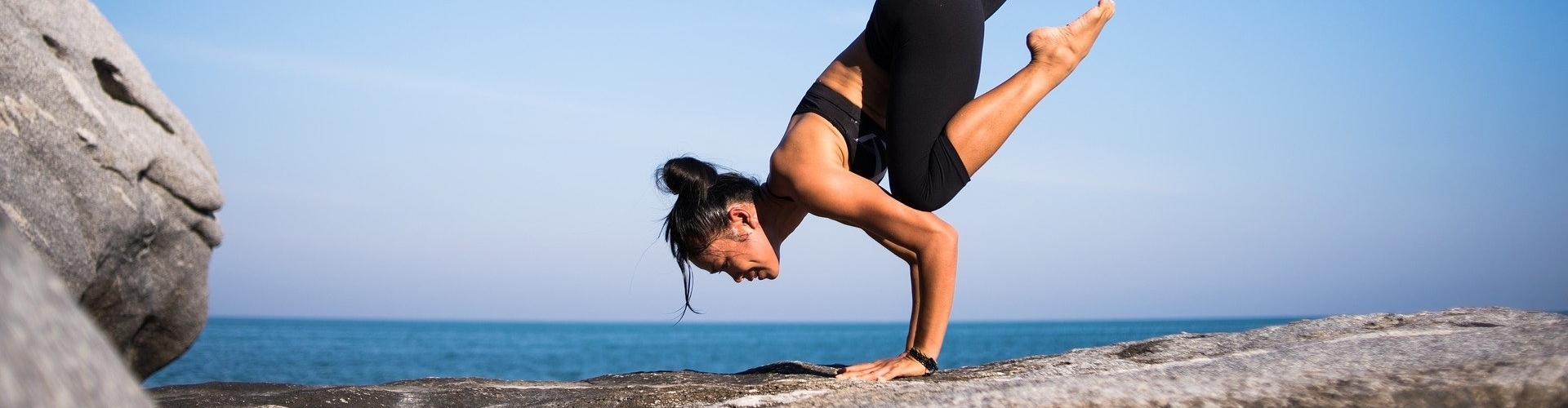 Een slanke vrouw op een rots die yoga beoefend