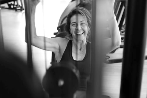 slanke vrouw met lach op haar gezicht in de sportschool