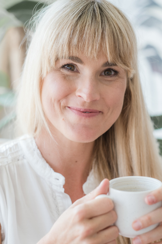 “Defje (Debby Minnart van Studio Jij)  lacht met een cappuccino in haar hand – koffie als ritueel en cultuur.