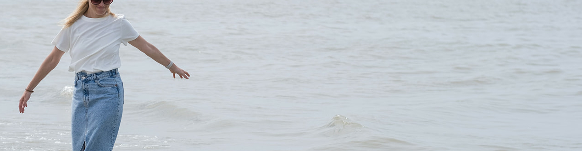 Defje van Studio Jij – gids in blokkades loslaten – wandelt blootsvoets aan zee. Thuiskomen bij jezelf, rust en vertrouwen vinden in Lede, Aalst en Gent via NEI sessies.