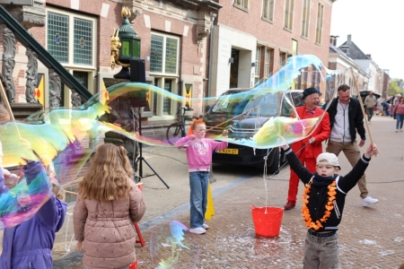 Bellenblaas artiest en kinderen die meedoen kinderen maken zeepbellen op het plein tijdens Koningsdag in Bolsward