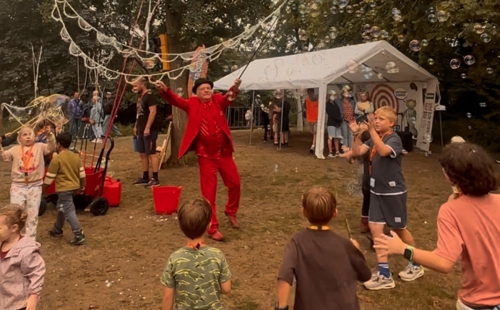 kinderen rennen achter de reuze zeepbellen aan
