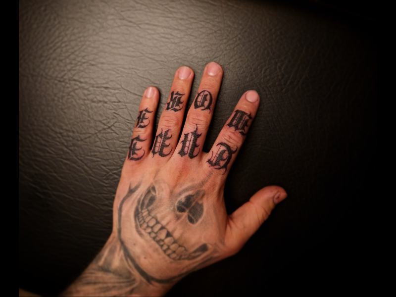 Lettering tattoo op vingers en hand