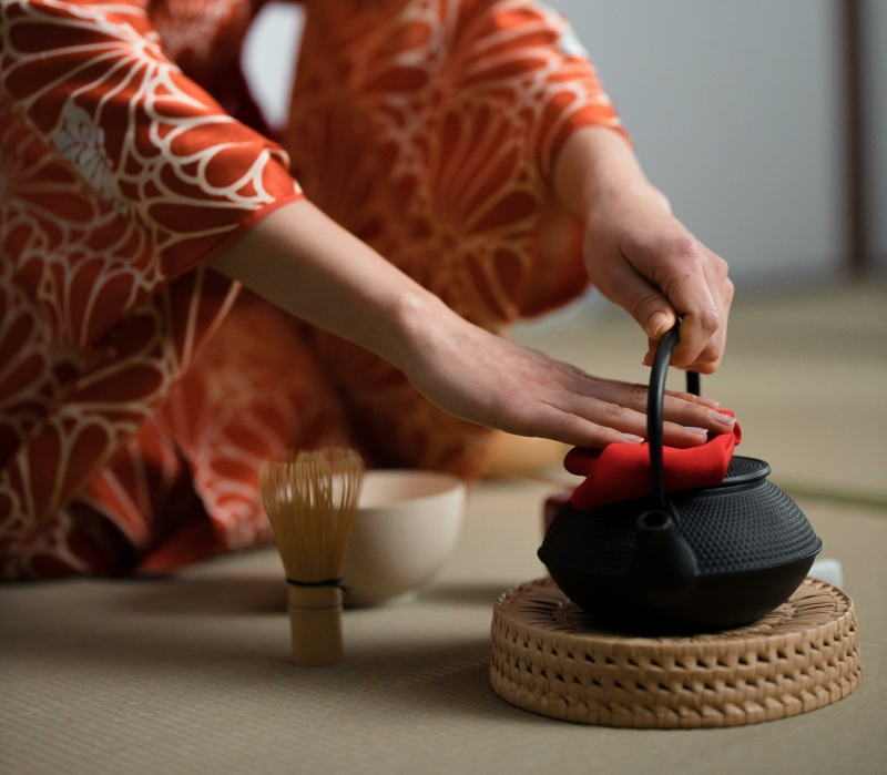 Thee ceremonie Japan met vrouw zit op de grond mettheepot en matcha attributen