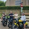 Vier personen op kleurrijke E-Choppers maken een tour door Texel tijdens een groepsuitje met TexelTours