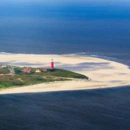 Luchtfoto van de vuurtoren van Texel bij De Cocksdorp, omringd door strand, duinen en zee