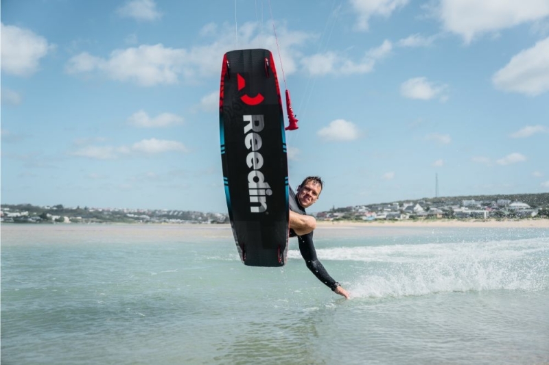 Close-up action shot of kitesurfer carving hard with REEDIN gear on choppy water