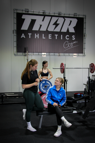 sporters die in de sportschool overleggen over de krachttraining en het leven.