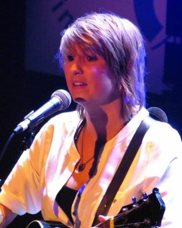 Evelyn Scholtens van der Stok zingend en gitaar spelend tijdens het COC Songfestival 2013, waar ze de derde plaats behaalde