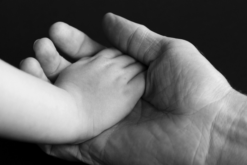 Volwassen hand houdt kinderhand vast symboliseert traumaverwerking en heling van het innerlijke kind