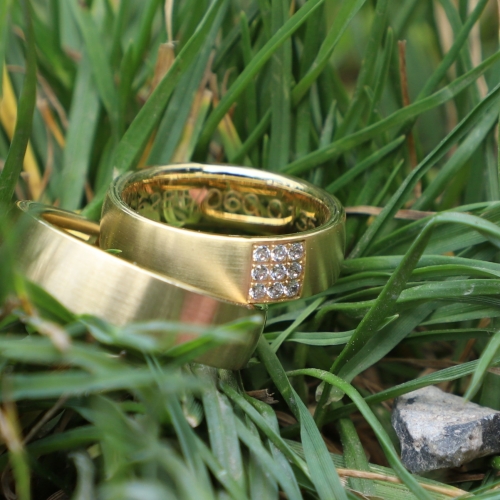 Gouden trouwringen met diamant in het gras