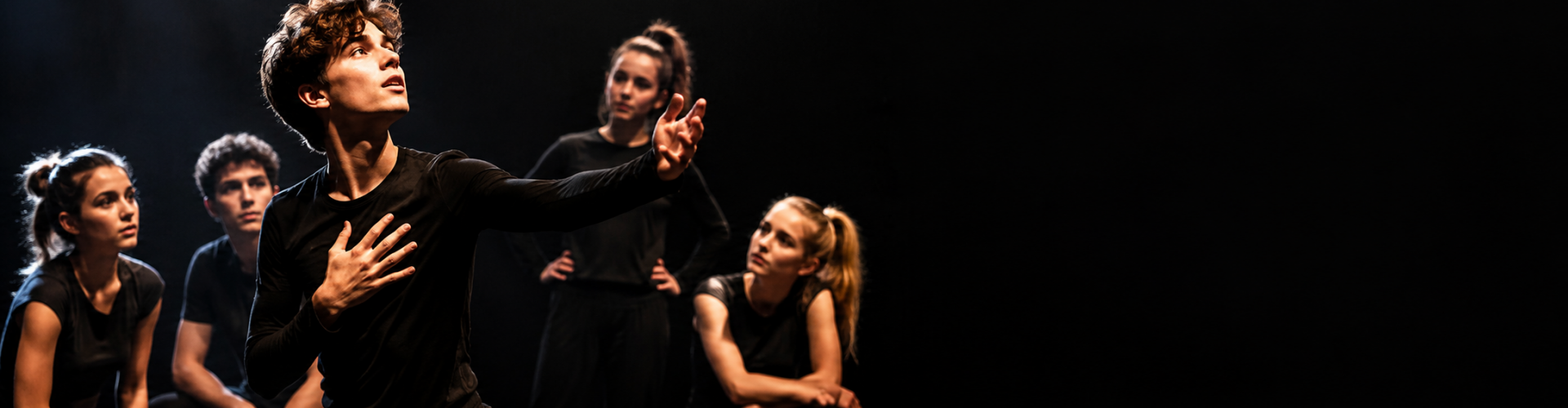 Jonge musicaltheaterspelers repeteren geconcentreerd in warm theaterlicht tijdens een selectieklas van VAYE.