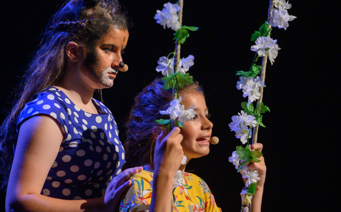 Twee jonge musicalspelers zingen en spelen samen in kostuum tijdens een musicaltheatervoorstelling van VAYE.