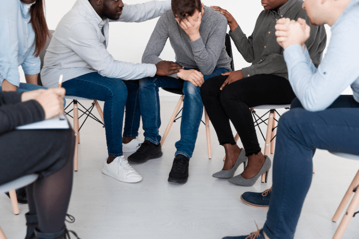 Een man die een ander troost, illustratie van empathie en emotionele ondersteuning binnen de herstelcommunity.
