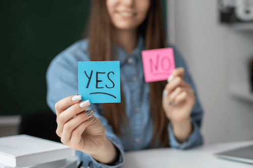 Vrouw houdt een post-it met 'Yes' omhoog als antwoord op de vraag: Is deze community iets voor jou?