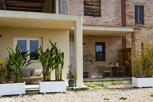 Overzicht van Vista Fermo met het gebouw waarin Appartement Luce is gevestigd, gelegeven in het groene Italiaanse heuvellandschap