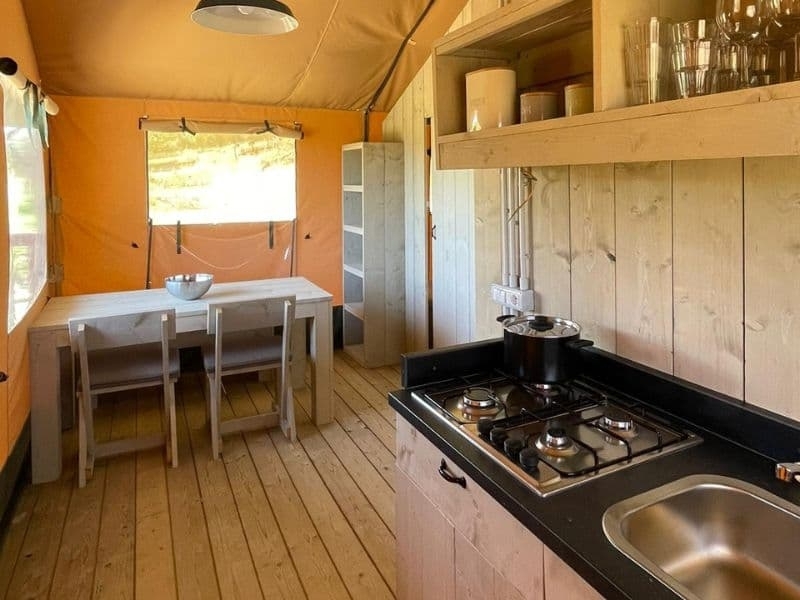 Binnenzijde van een safaritent met houten keuken, kookplaat en eethoek bij Vista Fermo in Le Marche