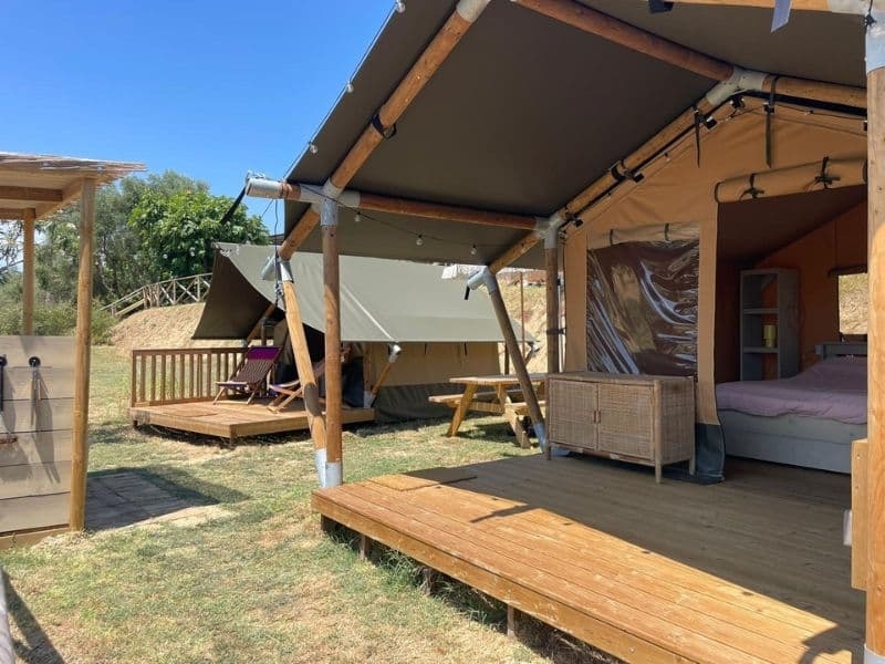 Meerdere safaritenten op het terrein van Vista Fermo met houten veranda's en zitplekken in het gras