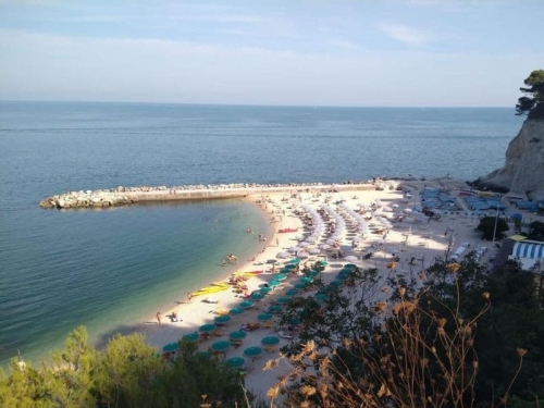 Zandstrand aan de Riviera del Conero met parasols en helderblauw water, een populaire dagtrip vanuit Vista Fermo