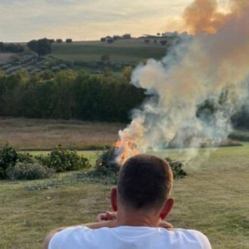 Man kijkt over het Italiaanse landschap naar een brandende stapel hout, symbool voor systemisch werk en loslaten