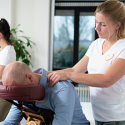 Mevrouw geeft stoelmassage aan een werknemer.