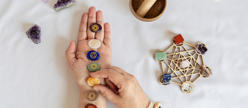 Hand met chakra-stenen en kristallen op witte ondergrond