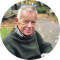 Portretfoto van Albert Konings buiten in een parkachtige omgeving met herfstbladeren.