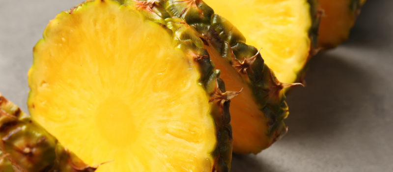 Close-up van sappig ananasplakje op grijze achtergrond, vers tropisch fruit