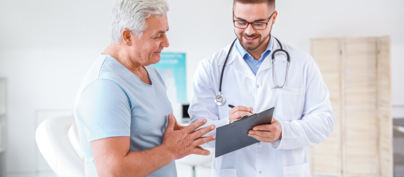 Arts praat met oudere man in kliniek, gezondheidsconsult