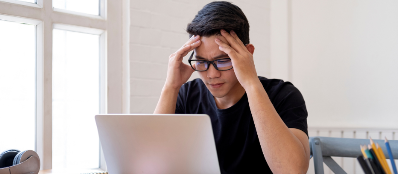 Man met bril kijkt geconcentreerd naar blauw computerscherm, blauw licht