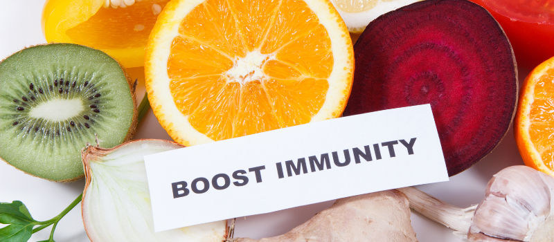 Woord “BOOST IMMUNITY” op kaartje tussen citrusvruchten en groenten, immuniteit boost