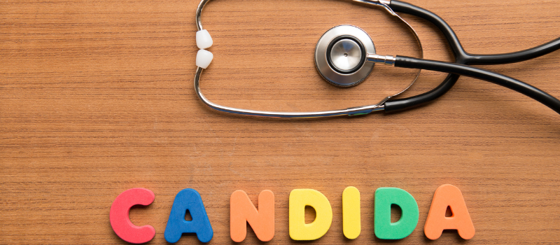 Het woord Candida in gekleurde letters met stethoscoop op houten tafel