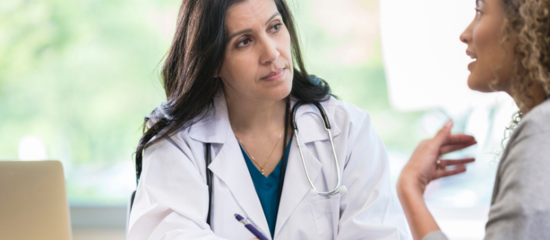 Vrouw bespreekt gezondheidsklachten met een dokter.