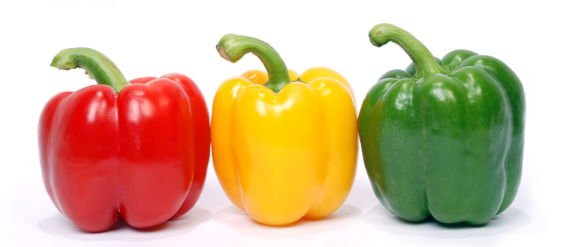 Rode, gele en groene paprika netjes naast elkaar op witte achtergrond