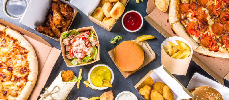 Pizza, friet, nuggets en burgers op tafel met sauzen